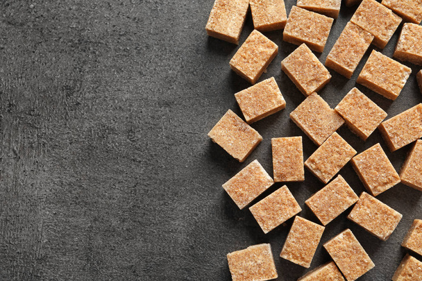 Cubes of brown sugar on gray background - Foto, afbeelding
