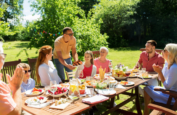 family having dinner or barbecue at summer garden - Foto, Imagen