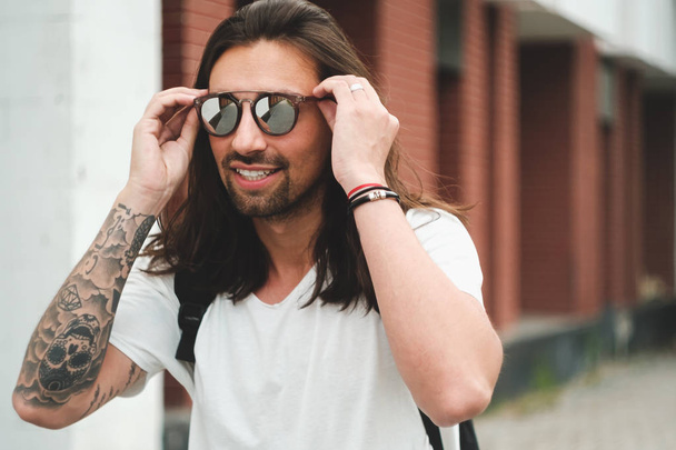 Πορτρέτο ελκυστικός άνδρας με γυαλιά ηλίου σε αστικό φόντο smil - Φωτογραφία, εικόνα