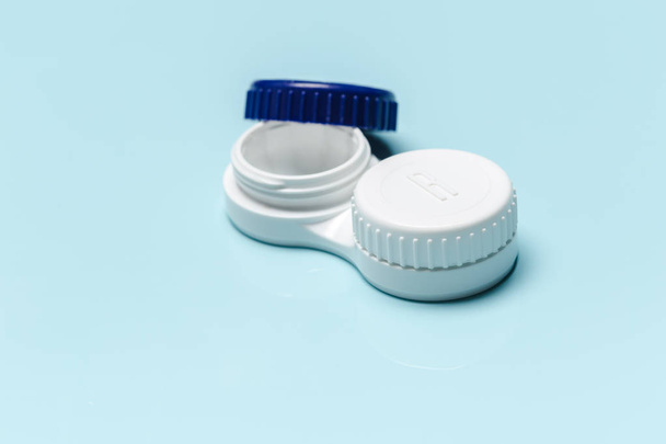 Contact lens, contact lens case, tweezers on blue background - Фото, зображення