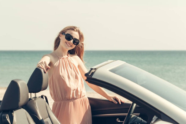 Young woman drive a car on the beach - Foto, afbeelding
