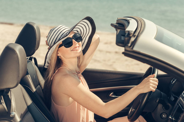 Jonge vrouw een auto rijden op het strand - Foto, afbeelding