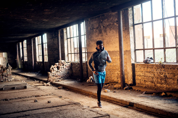 portrait of afro-american young handsome man with earphones training inside of abandoned place - Photo, Image