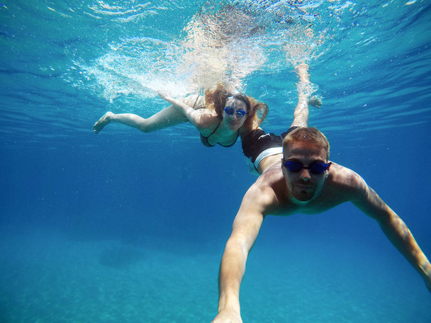 陽気なカップル楽しんで水中と selfiestick と selfie を取って - 写真・画像
