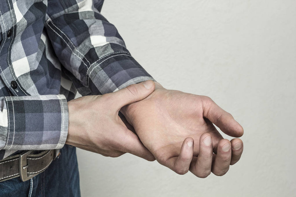 De pols van een man wordt gecontroleerd op zijn hand. Verstoorde bloeddruk. - Foto, afbeelding