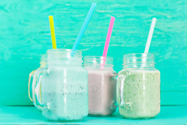 Closeup of jars with vegetable smoothies on green wall background - Photo, Image