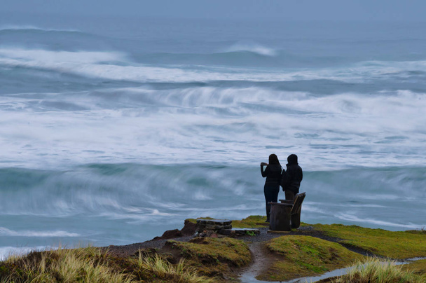 Pareja viendo el Océano Pacífico al atardecer en Oregon, State
 - Foto, Imagen