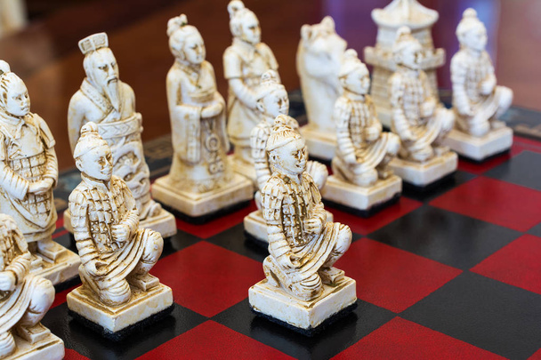 Piezas de ajedrez talladas en estilo chino en un tablero de ajedrez
. - Foto, Imagen