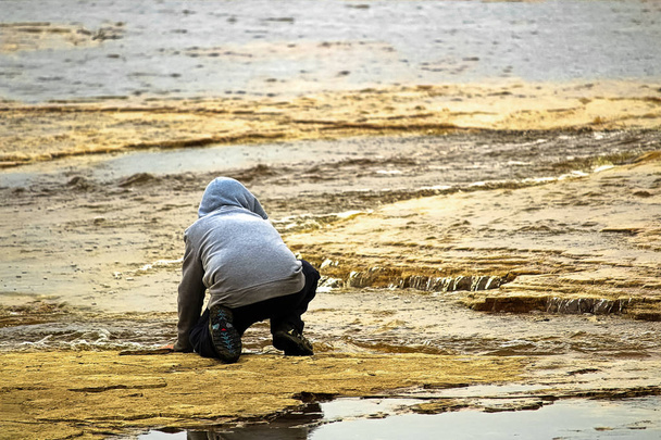 Un niño en el borde de un río observando el agua fluyendo
 - Foto, imagen