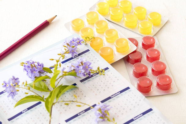 notebook calendario planner tosse mal di gola pastiglia e viola fiori su sfondo bianco
 - Foto, immagini