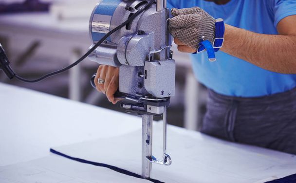 Cloth-cutting machine and masters hands in metal glove - Fotoğraf, Görsel