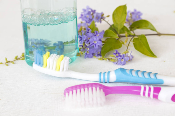 Mundspülung mit Zahnbürste für die Mundhöhle und lila Blume auf weißem Grund - Foto, Bild