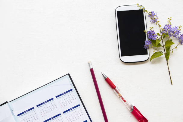 kannettavan suunnittelija kalenteri ja matkapuhelin liike violetti kukka pöydällä valkoinen
 - Valokuva, kuva