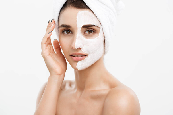 Beauty Skin Care Concept - Hermosa mujer caucásica retrato de la cara aplicando máscara de crema en su piel facial fondo blanco
. - Foto, imagen