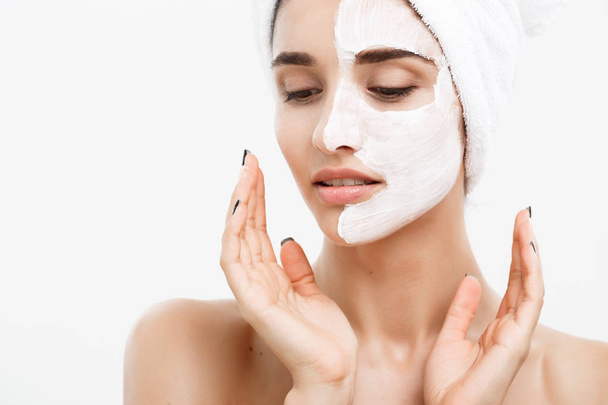 Beauty Skin Care Concept - Bella donna caucasica Ritratto viso applicare maschera crema sulla sua pelle del viso sfondo bianco
. - Foto, immagini