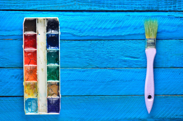 Une palette de peinture à l'aquarelle et un pinceau pour peindre sur des planches en bois bleu. Vue de dessus. Espace de copie. Concept d'art
 - Photo, image