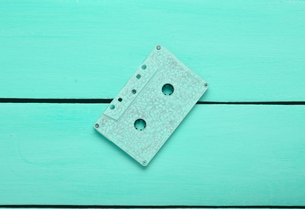 Retro audio cassette on a turquoise wooden background. Trend of minimalism. The concept of obsolete audio technology. Top view.  - Photo, Image