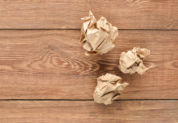Balls of crumpled old paper on a wooden table. The concept of inappropriate, spent ideas. - Photo, Image