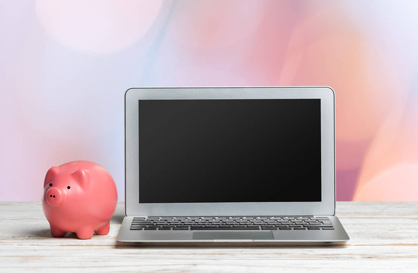 piggy bank and laptop on wooden table - Photo, image