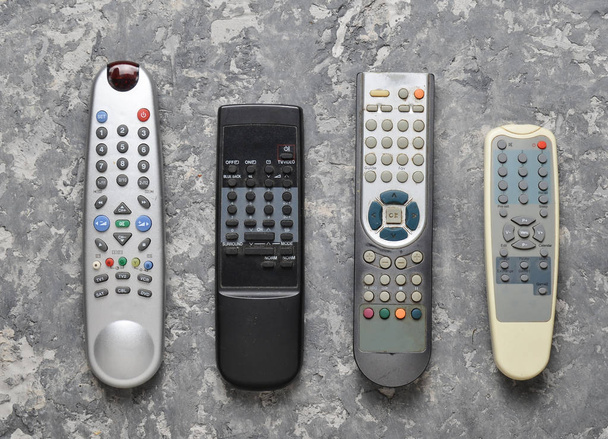 Many TV remotes on a gray concrete table. Top view. Remote control of home appliances and electronics. - Photo, Image