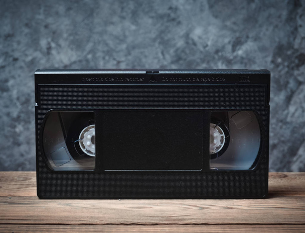 Cassette vidéo gros plan sur une étagère en bois contre un mur en béton gris. Technologie rétro pour regarder des vidéos
. - Photo, image
