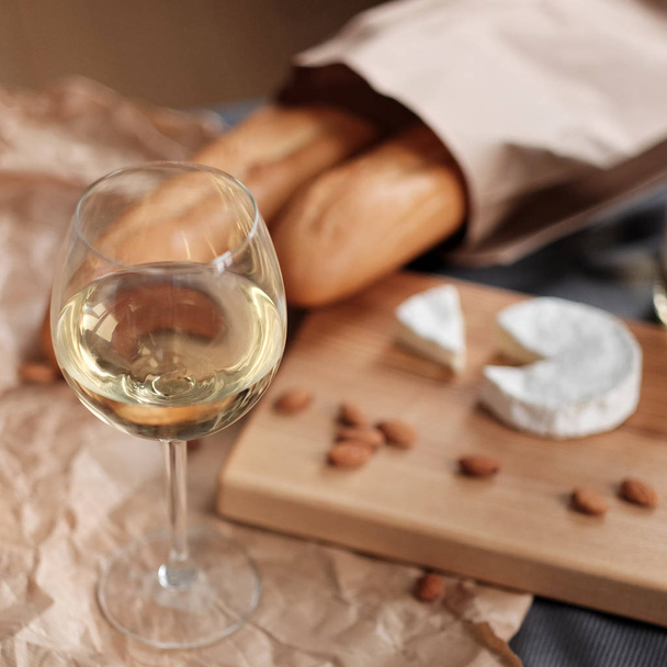 A glass of white wine and cheese on a blackboard - Фото, зображення