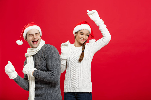 Χριστούγεννα έννοια - Happy νεαρό ζευγάρι στον sweatesr που γιορτάζει τα Χριστούγεννα με παιχνίδι και χορό - Φωτογραφία, εικόνα