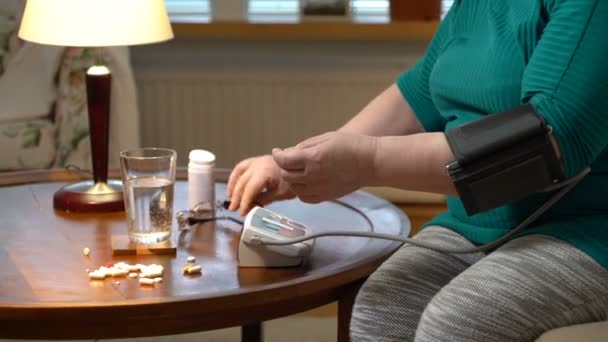 An elderly woman measures blood pressure and takes pills at home. - Séquence, vidéo