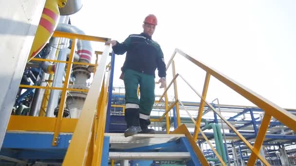 KAZAN, TATARSTAN/RUSSIA - AUGUST 21 2017: KAZAN, TATARSTAN/RUSSIA - AUGUST 21 2017: Slow motion closeup oil production plant worker climbs down stairs against pipelines and constructions on August 21 in Kazan on August 21 in Kazan - Video, Çekim