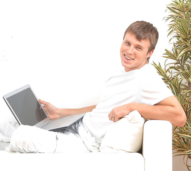 Very focused young man using laptop while sitting comfortably. - 写真・画像
