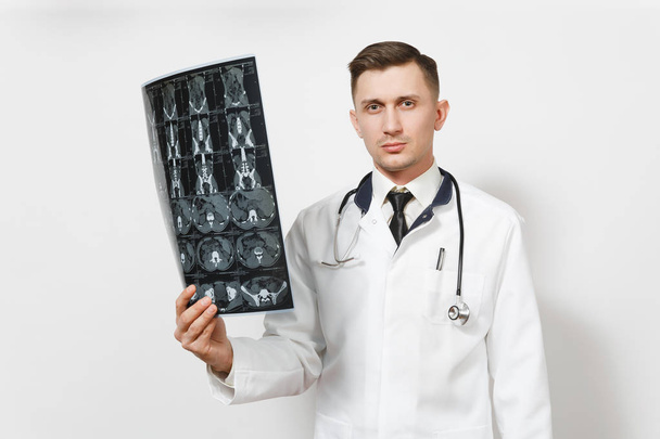 Ernstige knappe jonge dokter man houdt x-ray radiografisch beeld ct-scan die MRI geïsoleerd op een witte achtergrond. Mannelijke doctor in de medische uniforme, stethoscoop. Medisch personeel, gezondheid, geneeskunde concept. - Foto, afbeelding