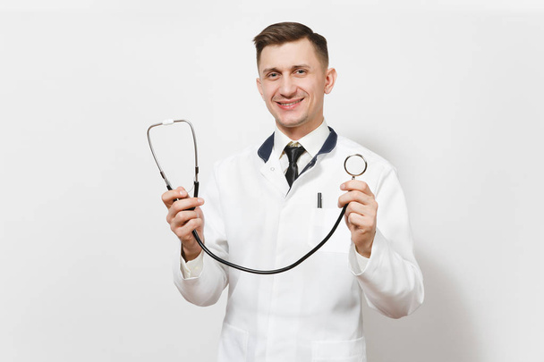Счастливый опытный молодой врач на белом фоне. Мужчина-врач в медицинской форме держит стетоскоп в протянутых руках. Здравоохранение, здравоохранение, медицина
. - Фото, изображение