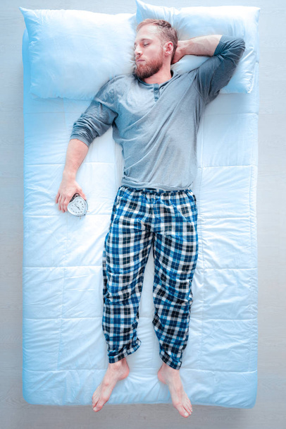 Sleepy man holding alarm clock - Zdjęcie, obraz