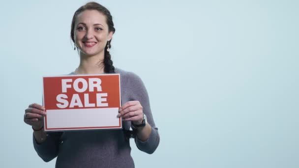 Smiling woman holding white sign board for sale - Filmagem, Vídeo