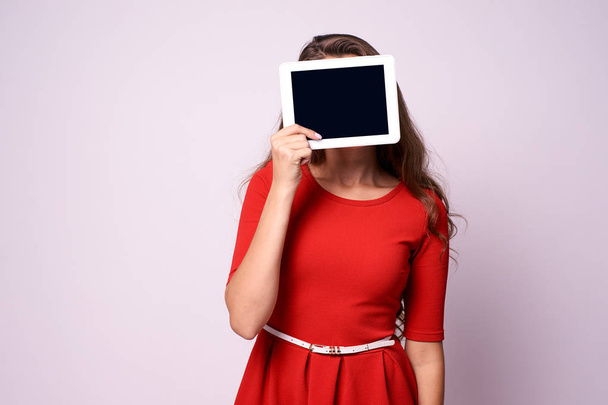 Girl with tablet. Modern technologies. Red dress - Foto, imagen