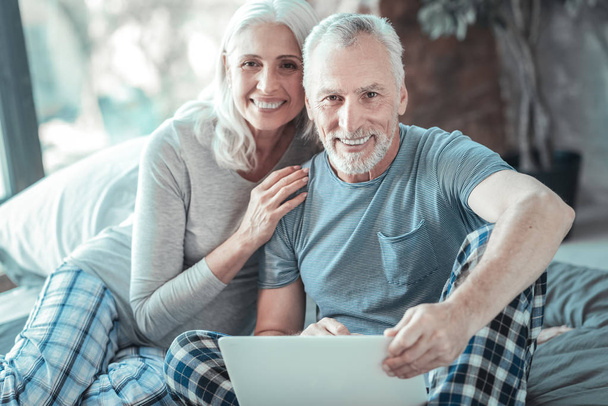 Satisfied aged couple sitting and smiling. - Foto, Bild
