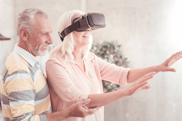 Cute satisfied woman using the VR glasses and smiling. - Фото, изображение