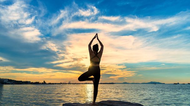 Silueta de yoga. Mujer de la meditación en el océano durante la puesta del sol increíble. Fitness y estilo de vida saludable
 - Foto, Imagen