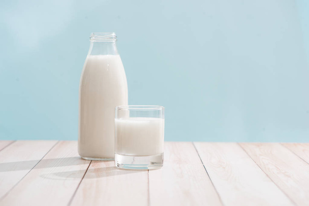 Молочные продукты. Бутылка с молоком и стакан молока на деревянном столе
 - Фото, изображение