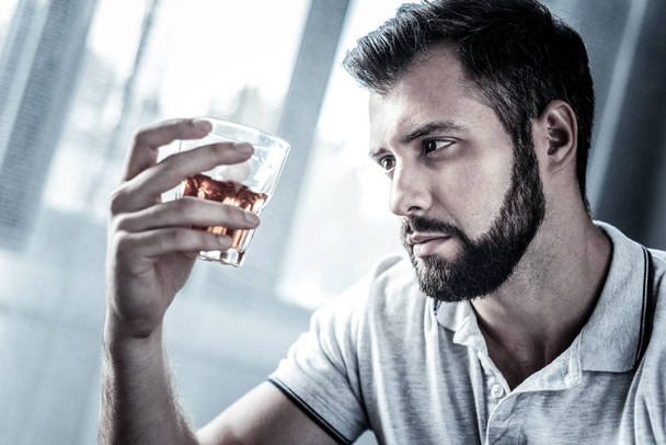 Sad upset man holding and looking at the glass. - 写真・画像