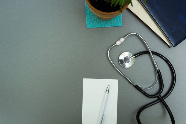The doctor's workplace. Notepad with pen, stethoscope and flower - Foto, Imagem