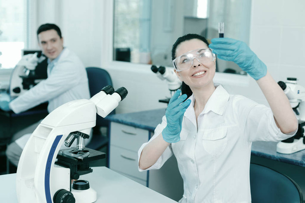 Blij jonge vrouw die werkt in het laboratorium - Foto, afbeelding