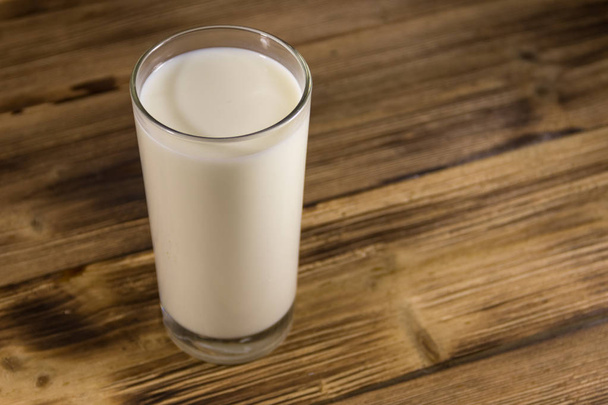 glas melk op houten tafel - Foto, afbeelding