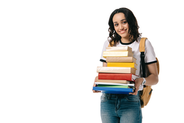 smiling african american teen student holding stack of books isolated on white - Фото, изображение