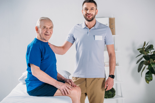 portrait de thérapeute en réadaptation et homme âgé souriant sur table de massage
 - Photo, image