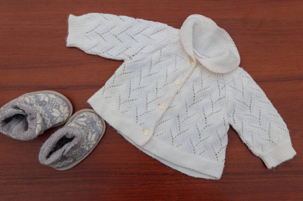 Babybekleidung und Stiefel auf Holzgrund - Foto, Bild