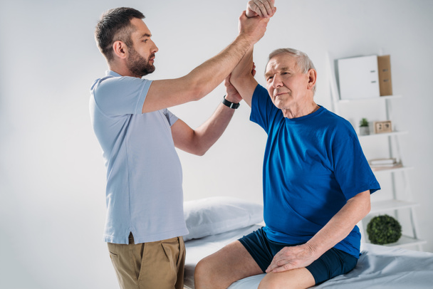 portrait of rehabilitation therapist doing massage to senior man on massage table - Foto, Bild