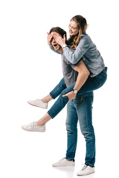 boyfriend giving piggyback to girlfriend and she covering eyes isolated on white - Fotografie, Obrázek
