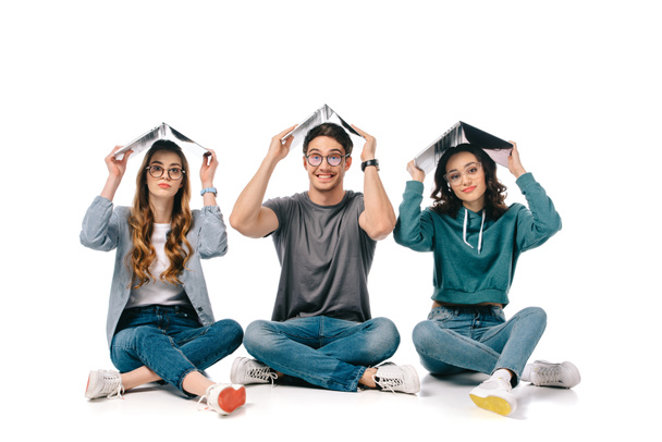 sorrindo estudantes multiculturais sentados com livros acima cabeças em branco
 - Foto, Imagem