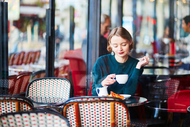 Young elegant woman drinking coffee in traditional cafe in Paris, France - Фото, зображення